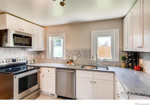 kitchen featuring white cabinetry, a healthy amount of sunlight, appliances with stainless steel finishes, and sink