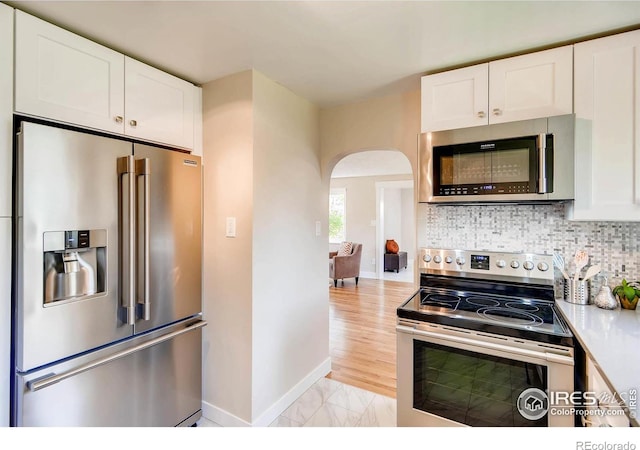 kitchen featuring appliances with stainless steel finishes, white cabinets, and decorative backsplash