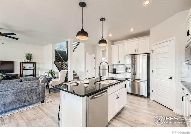 kitchen featuring sink, stainless steel appliances, backsplash, a kitchen island with sink, and white cabinets