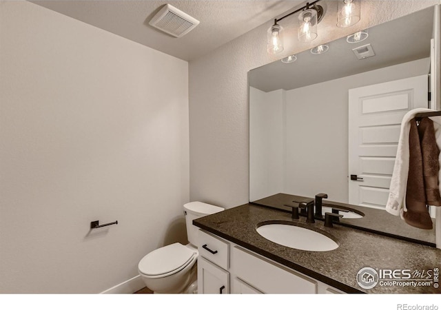 bathroom featuring vanity, a textured ceiling, and toilet