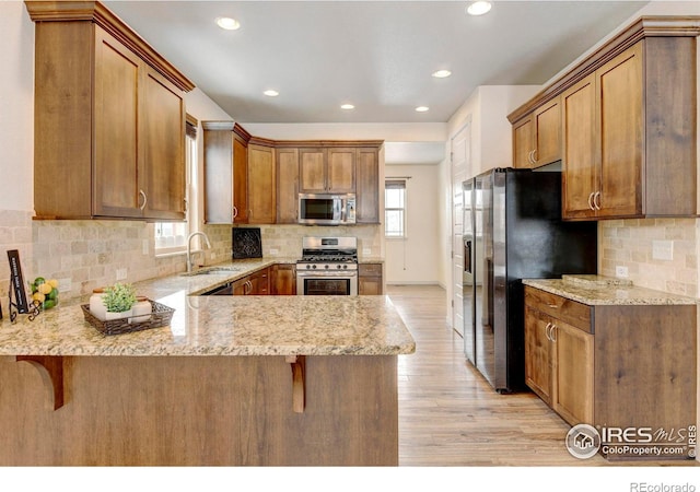 kitchen with a peninsula, appliances with stainless steel finishes, a breakfast bar area, and a sink