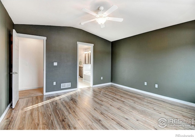 unfurnished bedroom with vaulted ceiling, baseboards, visible vents, and light wood-style floors