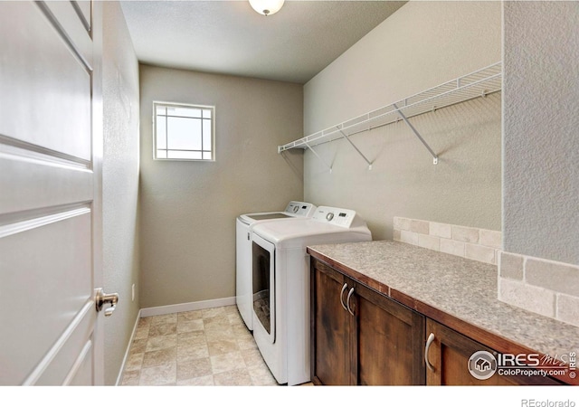 laundry area with independent washer and dryer, cabinet space, and baseboards