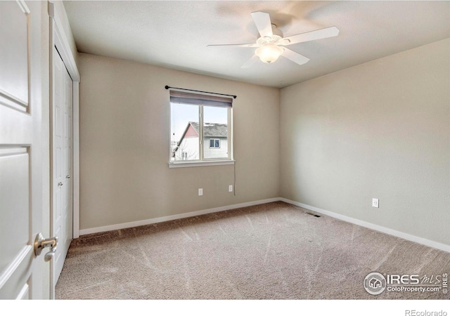 unfurnished bedroom with a closet, light colored carpet, visible vents, a ceiling fan, and baseboards