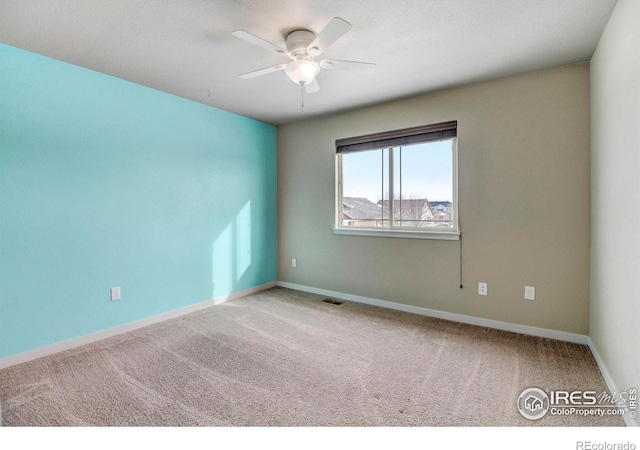 empty room with carpet, visible vents, ceiling fan, and baseboards