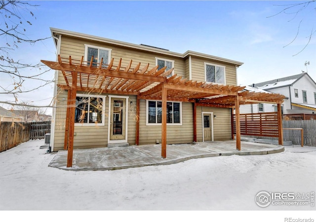 snow covered property with a fenced backyard and a pergola