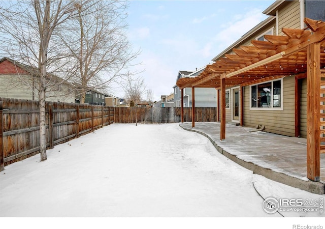 snowy yard with a fenced backyard and a pergola