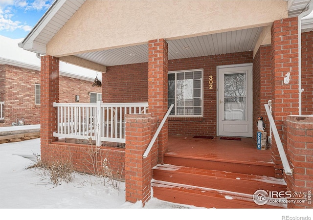 snow covered property entrance with a porch