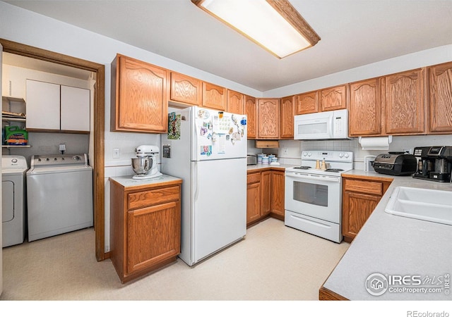 kitchen with washer and clothes dryer, sink, and white appliances