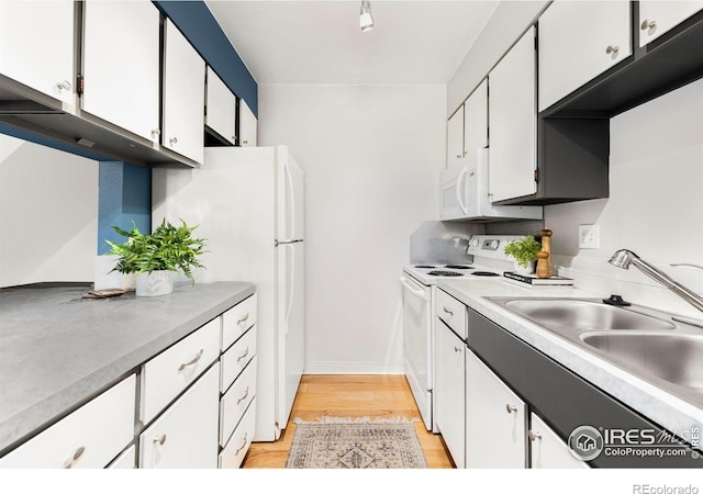 kitchen with white cabinets, white appliances, light hardwood / wood-style flooring, and sink