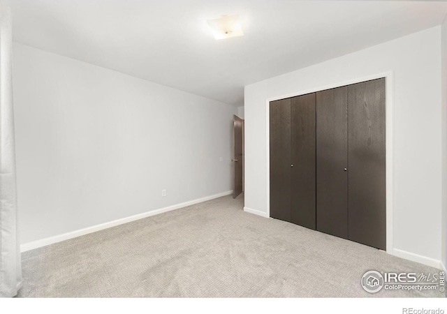 unfurnished bedroom featuring a closet and light colored carpet