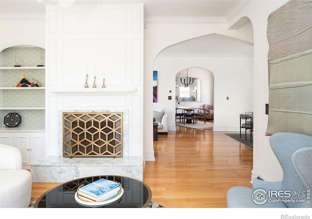 living room featuring hardwood / wood-style floors, built in features, and ornamental molding