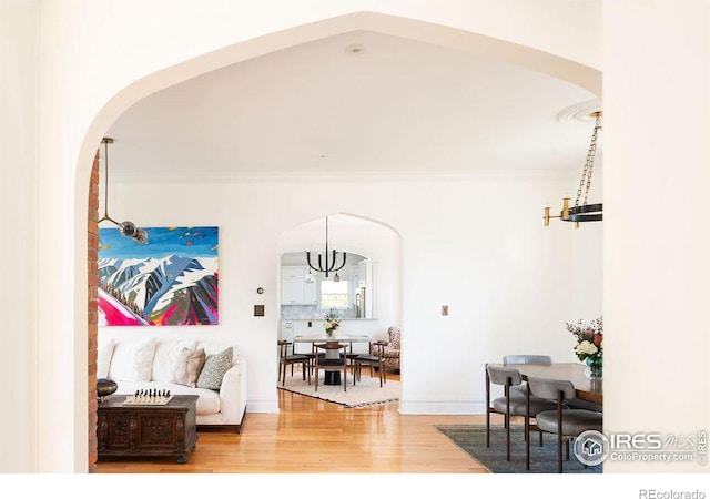 living room featuring hardwood / wood-style flooring, a notable chandelier, and crown molding