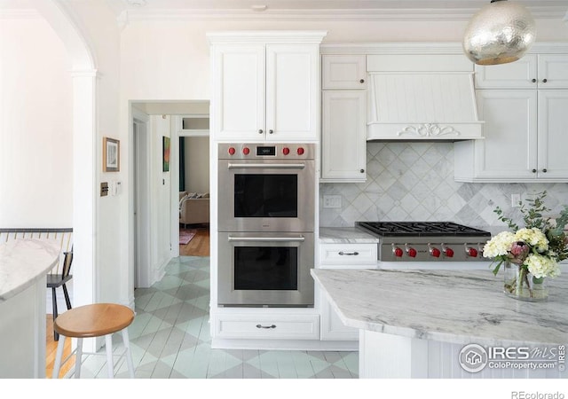 kitchen with white cabinets, a breakfast bar, appliances with stainless steel finishes, and tasteful backsplash