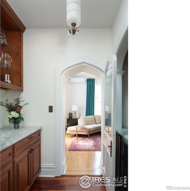 hall featuring dark hardwood / wood-style flooring, an AC wall unit, and an inviting chandelier