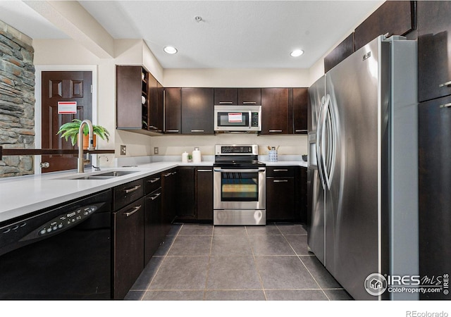 kitchen featuring sink, dark brown cabinetry, appliances with stainless steel finishes, and dark tile patterned floors