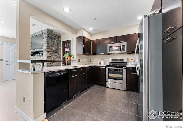 kitchen featuring kitchen peninsula, dark brown cabinets, dark tile patterned floors, sink, and stainless steel appliances