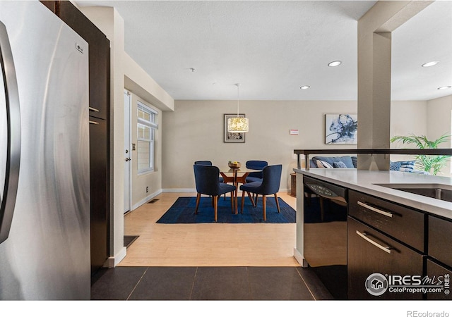 kitchen with dishwasher, hanging light fixtures, stainless steel refrigerator, sink, and dark brown cabinetry