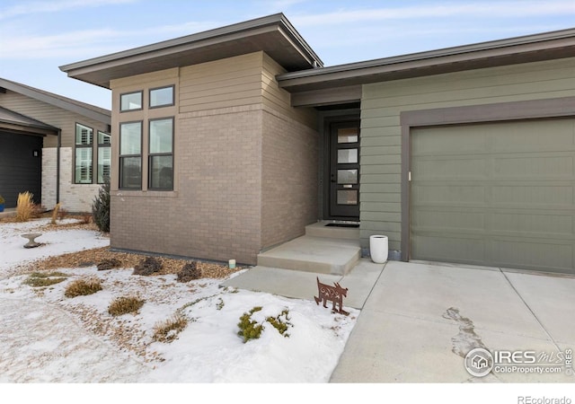 snow covered property entrance with a garage