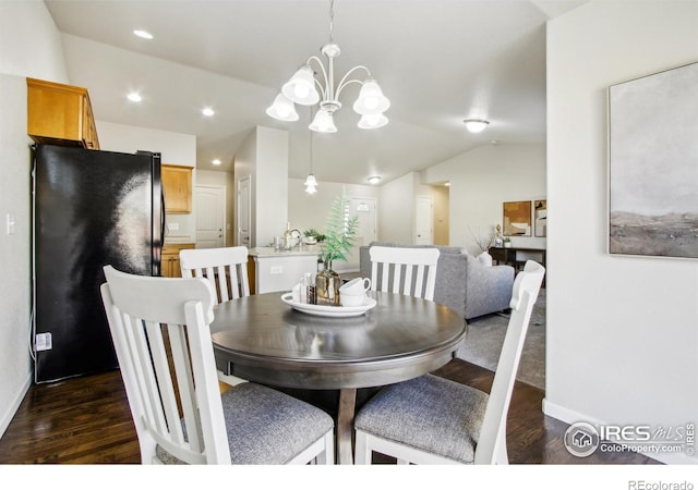 dining room with dark wood-type flooring, sink, lofted ceiling, and a chandelier