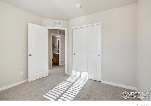 unfurnished bedroom with light carpet and a closet