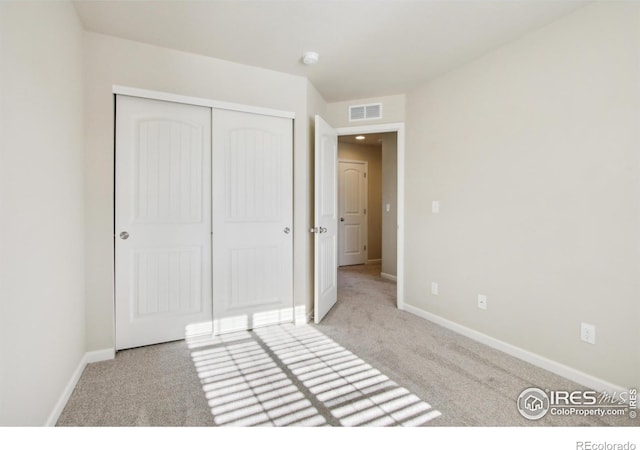 unfurnished bedroom with a closet and light colored carpet