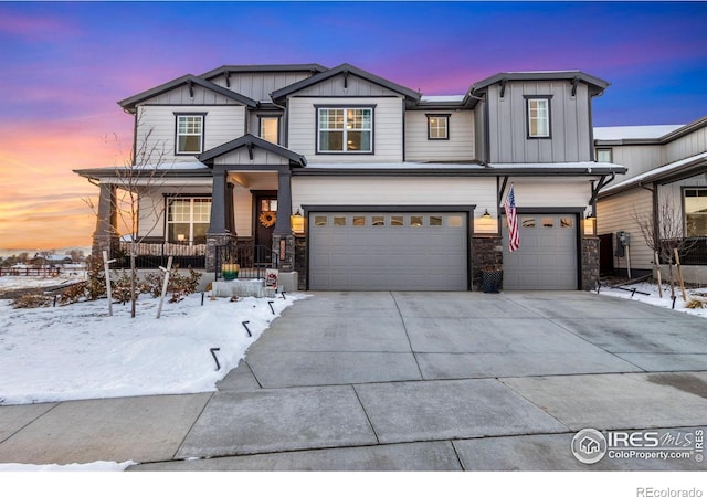 view of front of home with a porch, a garage, concrete driveway, stone siding, and board and batten siding