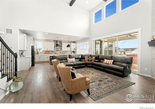 living room with a high ceiling, ceiling fan, and hardwood / wood-style floors