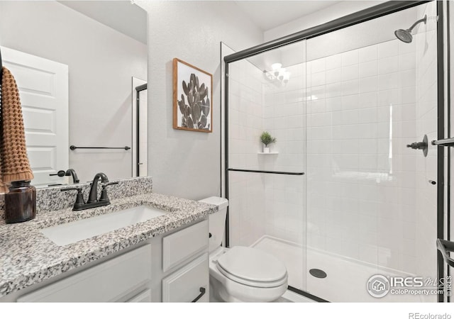 bathroom featuring toilet, a shower with door, and vanity