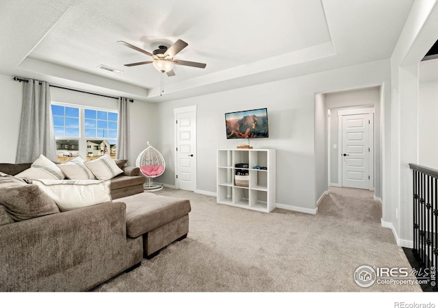 living room with light carpet, ceiling fan, and a tray ceiling