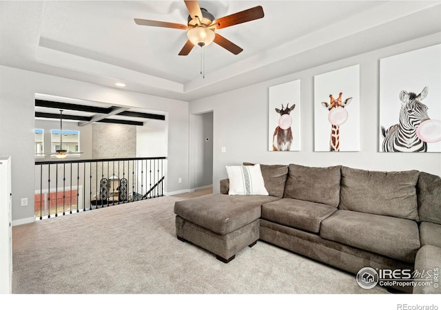 carpeted living room featuring ceiling fan and a tray ceiling