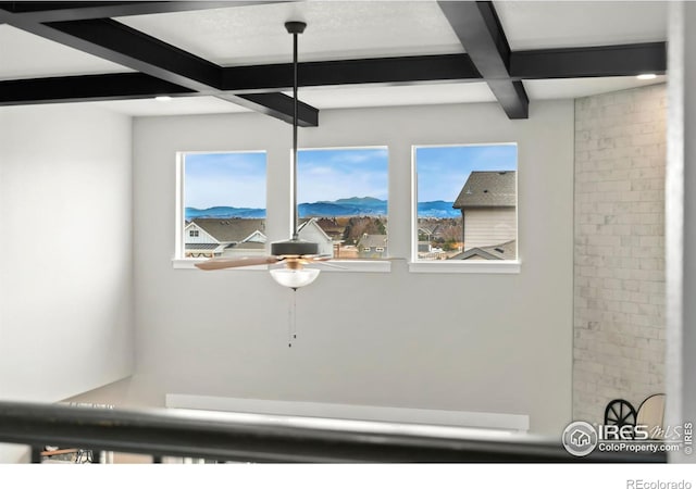 interior details featuring coffered ceiling, beamed ceiling, ceiling fan, and a mountain view