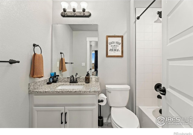 full bathroom with tiled shower / bath, vanity, and toilet