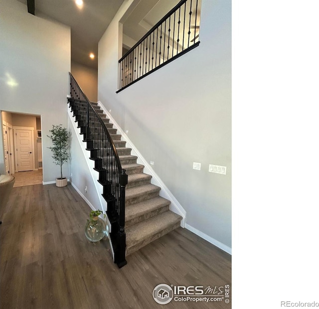 stairs with a high ceiling and hardwood / wood-style flooring