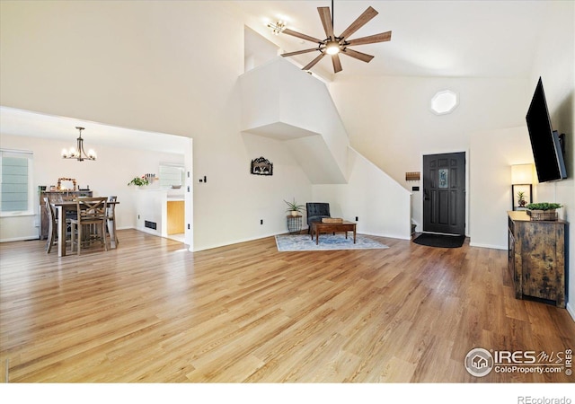 living room with ceiling fan with notable chandelier and light hardwood / wood-style flooring