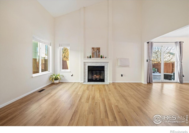 unfurnished living room with high vaulted ceiling and light hardwood / wood-style flooring