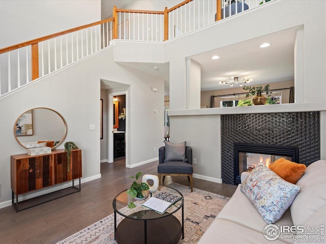 living room with a towering ceiling, a tile fireplace, and dark hardwood / wood-style floors