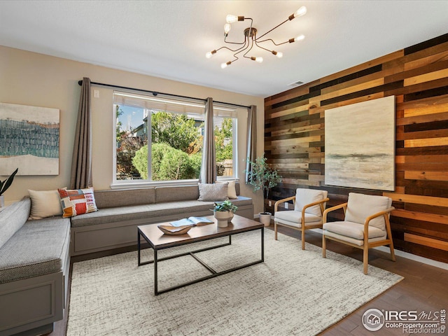 living room with a notable chandelier, wooden walls, and wood-type flooring