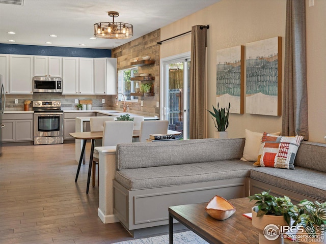 living room featuring an inviting chandelier, light hardwood / wood-style floors, and sink