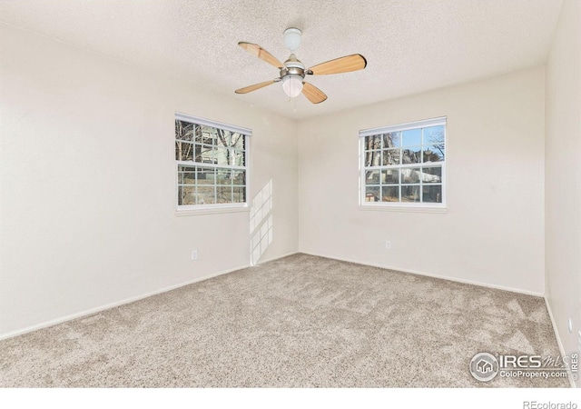 carpeted empty room with ceiling fan, plenty of natural light, and a textured ceiling