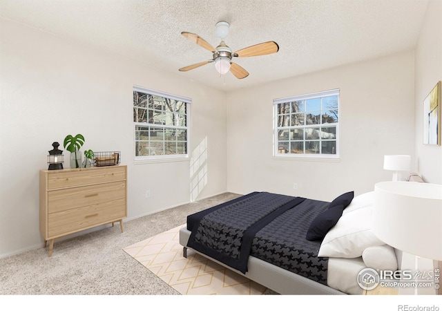 bedroom featuring ceiling fan, light carpet, and a textured ceiling