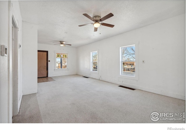 carpeted spare room with a textured ceiling and ceiling fan