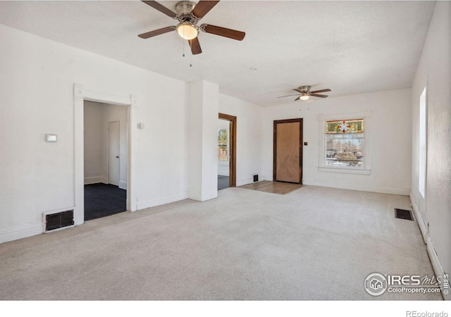 carpeted spare room featuring a textured ceiling and ceiling fan