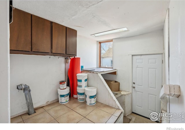 clothes washing area featuring a textured ceiling and light tile patterned floors