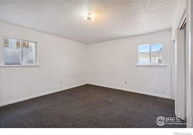 carpeted empty room featuring a textured ceiling