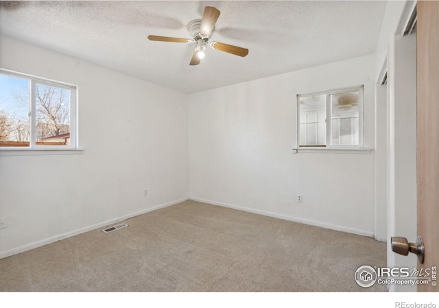 empty room featuring light colored carpet, ceiling fan, and a textured ceiling