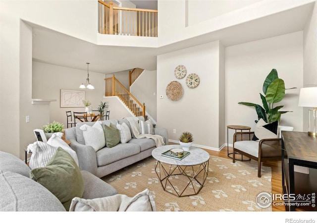 living room with a high ceiling, an inviting chandelier, and light wood-type flooring