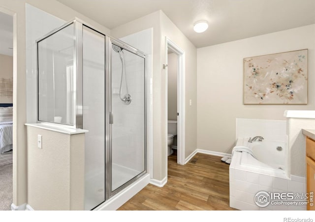 full bathroom featuring toilet, plus walk in shower, vanity, and hardwood / wood-style floors