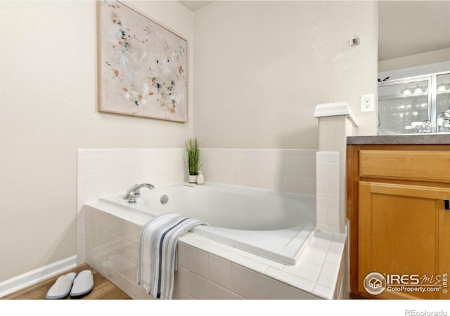 bathroom featuring tiled tub and vanity