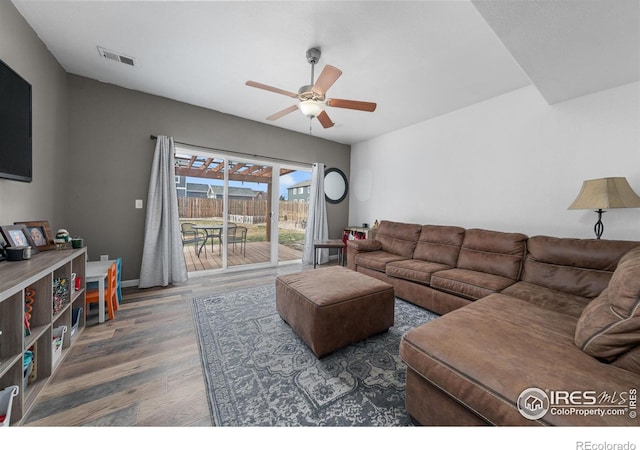 living room featuring ceiling fan and dark hardwood / wood-style floors